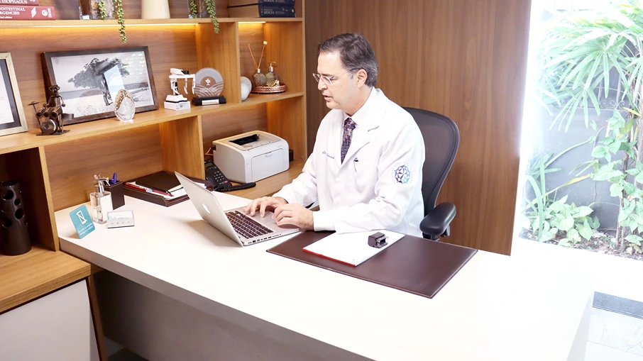 Fotografia representando o médico especialista Dr. Nilton Aranha trabalhando em um escritório, digitando em um computador. O instituto médico Gastrocamp oferece uma vasta seleção de tratamentos realizados por profissionais especializados e prontos para atender sua necessidade.