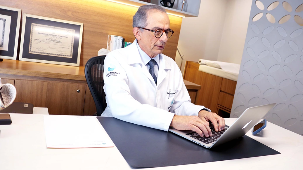 Fotografia representando o médico especialista Dr. Nilton Aranha trabalhando em um escritório, digitando em um computador. O instituto médico Gastrocamp oferece uma vasta seleção de tratamentos realizados por profissionais especializados e prontos para atender sua necessidade.